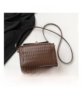 Dettaglio borsa a scatola marrone scuro con texture ondulata e chiusura a scatto dorata