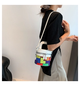 Detailed side view of colorful geometric cylinder bucket bag with white leather straps