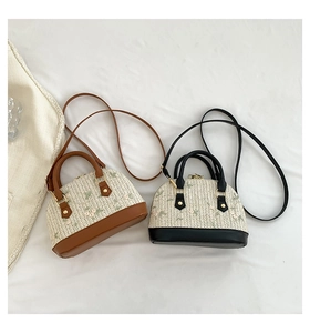 Detail of shell-shaped straw bags with floral embroidery and leather handles in two colors