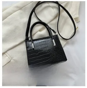 Top view of black crocodile pattern handbag with silver hardware next to a phone
