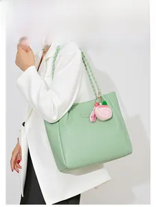 Détail du sac cabas en cuir gaufré vert menthe avec anses tressées et breloque pêche