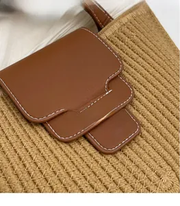 Macro detail of beige woven straw body with brown leather flap and contrast stitching