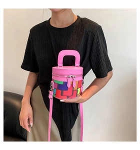 Detail of pink cylinder bag showing the colorful patchwork and dual silver zippers