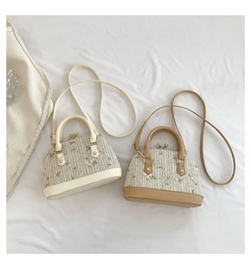 Flat lay of two straw shell bags featuring floral embroidery and leather handles