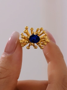 Detail of 18K gold ring featuring an oval blue gemstone with sunburst radial design