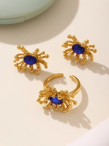 Detail of gold flower jewelry set featuring blue zircon inlay rings and stud earrings