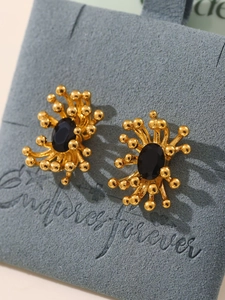 Macro view of 18K gold plated stud earrings with black stone and sunburst stamen design