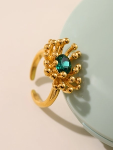 Detailed macro view of adjustable golden flower ring with green zircon center