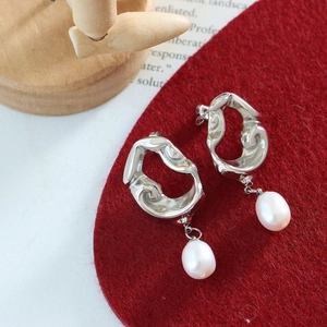 Détails macro des boucles d'oreilles ajourées en argent avec pendentifs perles blanches