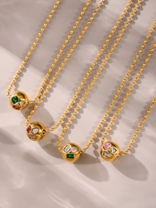 Detalle de cadenas de bolas doradas con colgantes esféricos y circonitas de colores