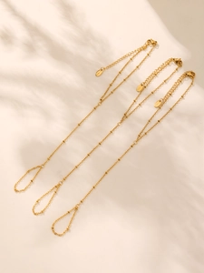 Macro shot of 18K gold plated bead chain jewelry with lobster clasp on beige background