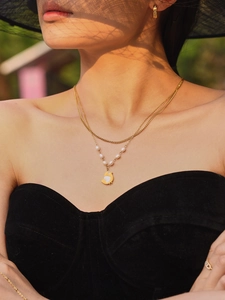 Detail einer zweilagigen Goldkette mit kleinen Perlen und Vogelanhänger an einem Modell