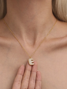 Gros plan sur le collier lettre E dorée avec zircons 5A étincelants sur la clavicule