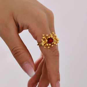 Elegant gold ring with oval red gemstone and radiant metal petal setting on finger