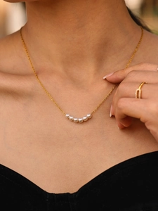 Dettaglio della collana in acciaio inossidabile placcato oro 18K con sei perle sulla modella