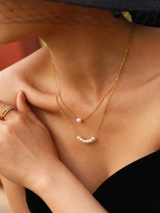 Elegante collana di perle a doppio strato dorata e anello brillante sulla modella
