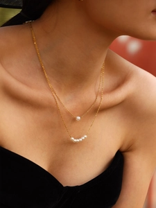 Primo piano della collana a doppio strato in oro con sei perle bianche sulla modella