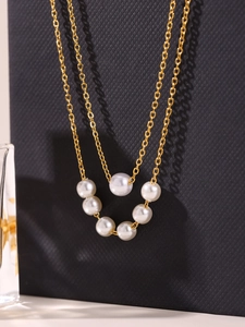 Dettaglio collana a doppio strato placcata oro 18k con perle su sfondo nero di lusso