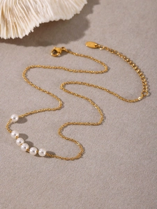 Dettaglio della collana in acciaio inossidabile placcato oro 18K con sei perle bianche