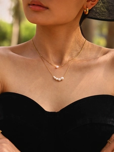 Close-up of double-layered gold stainless steel necklace with elegant white pearls