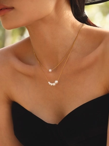 Close-up of double-layer gold chain necklace with lustrous white pearls on a model