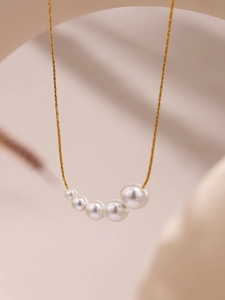 Close-up of five gradient pearls on a gold-plated necklace with a minimal luxury design