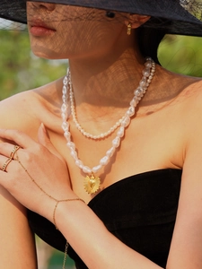 Detailed view of ocean style pearl necklace set with golden sun pendant on model
