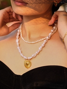 Close-up of double-layered pearl necklace with golden sacred heart pendant on model
