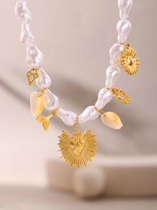 Detail of baroque pearl necklace with gold starfish, heart, and shell charms