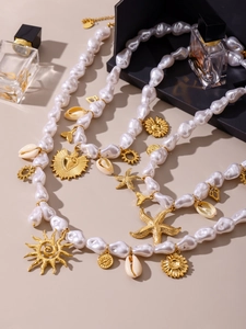 Baroque pearl necklace set with gold starfish, shell, and sun charms in a macro view