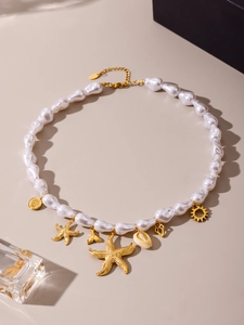 Macro detail of bohemian pearl necklace with golden starfish and seashell charms