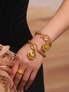 Detail of vintage gold OT-buckle chain bracelet with coin charms and textured ring