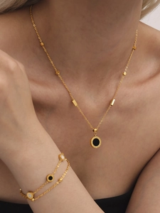 Nahaufnahme von Goldhalskette und Doppelarmband mit römischen Ziffern in Schwarz und Weiß