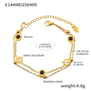 Detail eines 18k vergoldeten Doppelarmbands mit schwarzem Zirkon und weißer Muschel