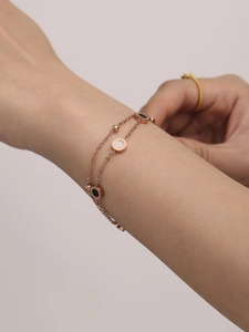 Detailaufnahme des doppellagigen Armbands in Roségold mit schwarz-weißen Anhängern