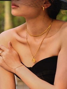 Détail du pendentif tournesol et de l'ensemble de bijoux dorés portés par un mannequin