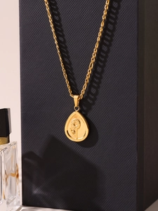 Vue détaillée du pendentif tournesol en relief sur un collier chaîne Figaro dorée