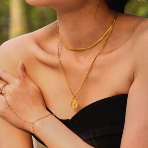 Collier double couche doré avec pendentif tournesol et bracelet bague sous une lumière chaude