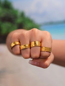 Detailed view of four mixed gold-plated rings including skull and smile designs
