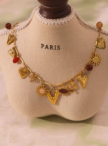 Detail of 18k gold multi-element necklace with colorful enamel hearts and natural stones
