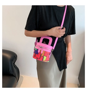 Detail view of colorful checkered cylindrical bag with pink leather strap and zipper closure