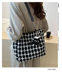 Detail of houndstooth tweed tote bag featuring silver metal chain and plush charm