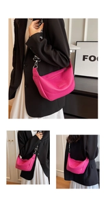 Gros plan du sac hobo en cuir fuchsia avec texte embossé et bandoulière en toile