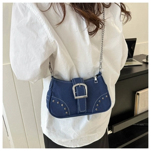 Detail of blue denim underarm bag featuring silver rivets and metal buckle hardware