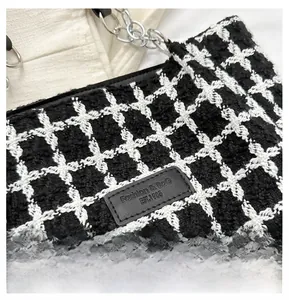 Detail of black and white tweed fabric texture with a brand label and metal chain strap