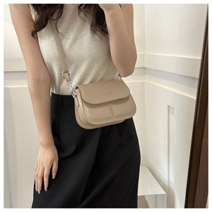 Spiegelselfie van de beige crossbodytas met reliëfopdruk van de modetrendtekst