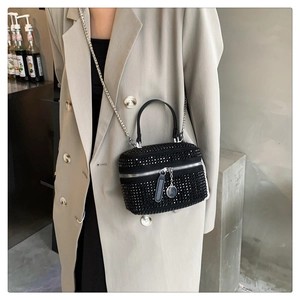 Detail of elegant black rhinestone handbag with silver chain strap on a chic outfit