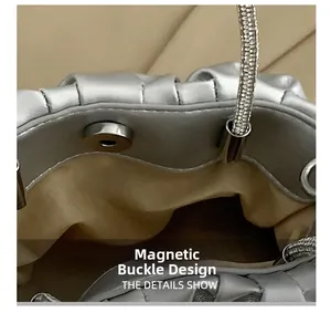 Detail of silver metallic purse featuring secure magnetic closure and rhinestone strap