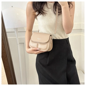 Detail van beige crossbodytas met textuurplooien en Fashion Trend belettering detail