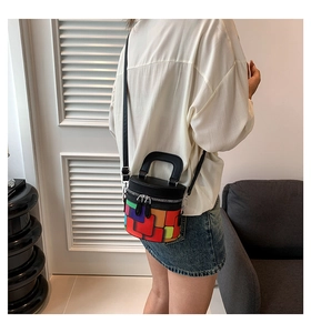 Detailed shot of a colorful geometric cylinder bucket bag with black leather handle and strap